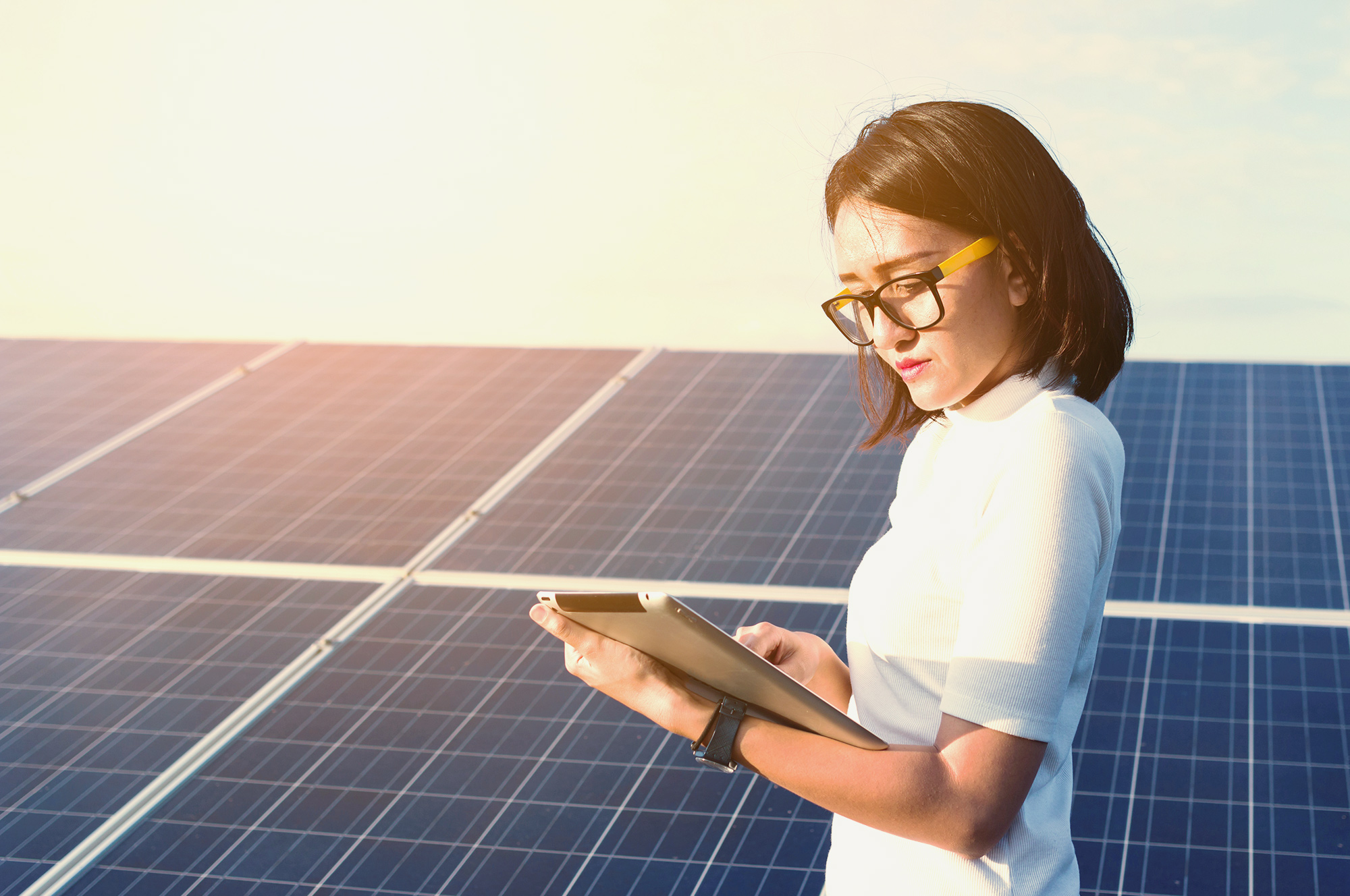 woman standing with computer in front of solar panels