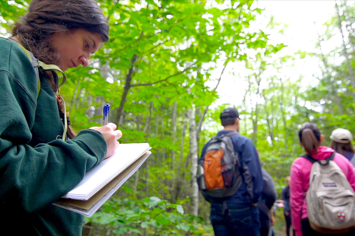 Student takes notes during an outdoor walk with other students