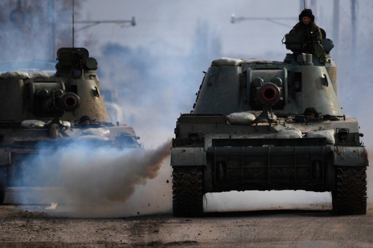Russian tanks drive down a street in Ukraine.