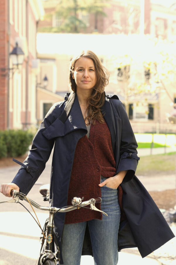Dorottya Barna poses with her bike on in front of a brick building.