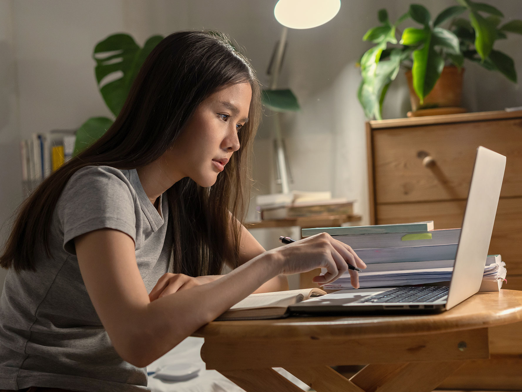A woman sits hunched over a laptop on a small desk.
