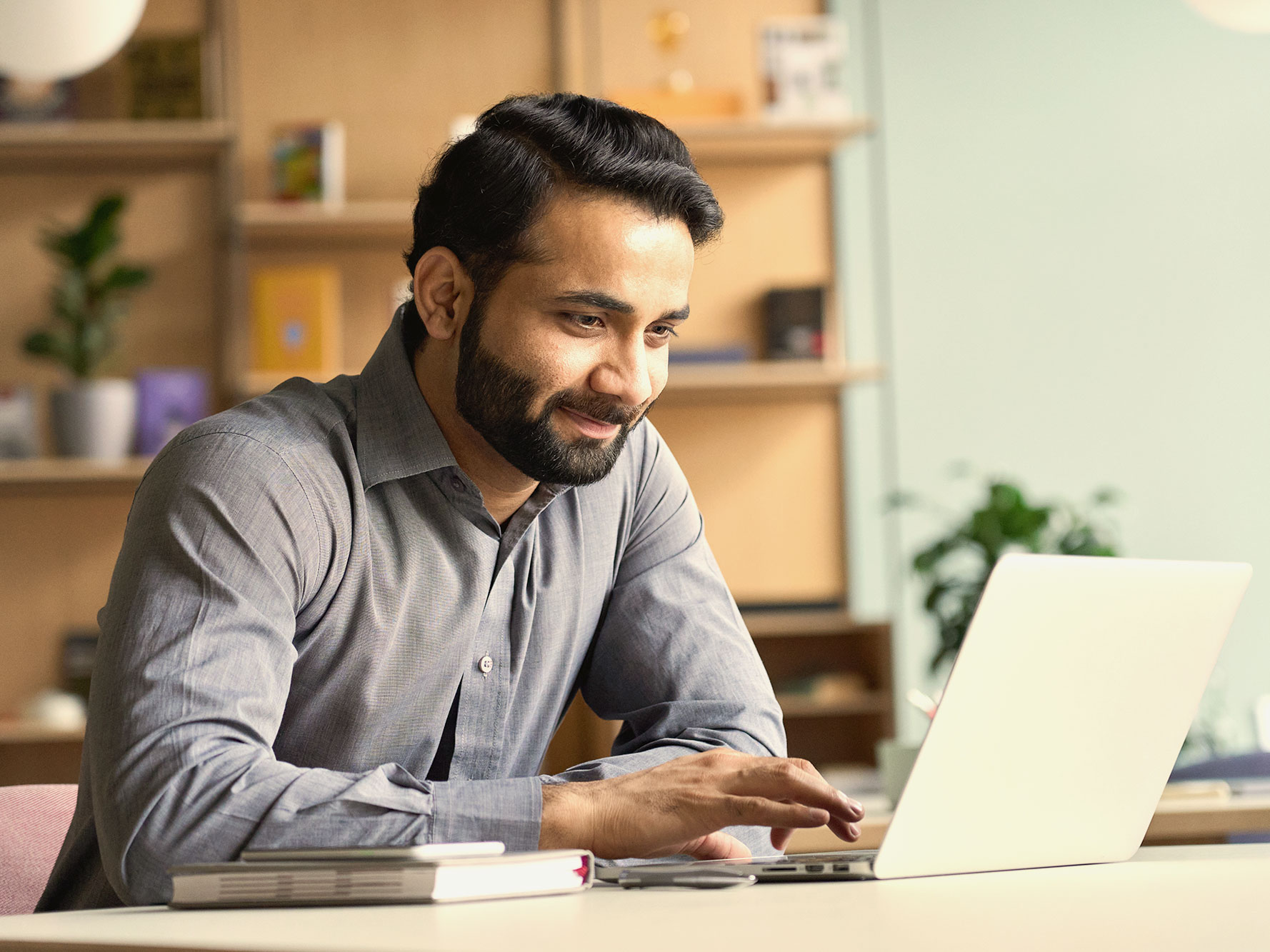 A smiling man works at a laptop.