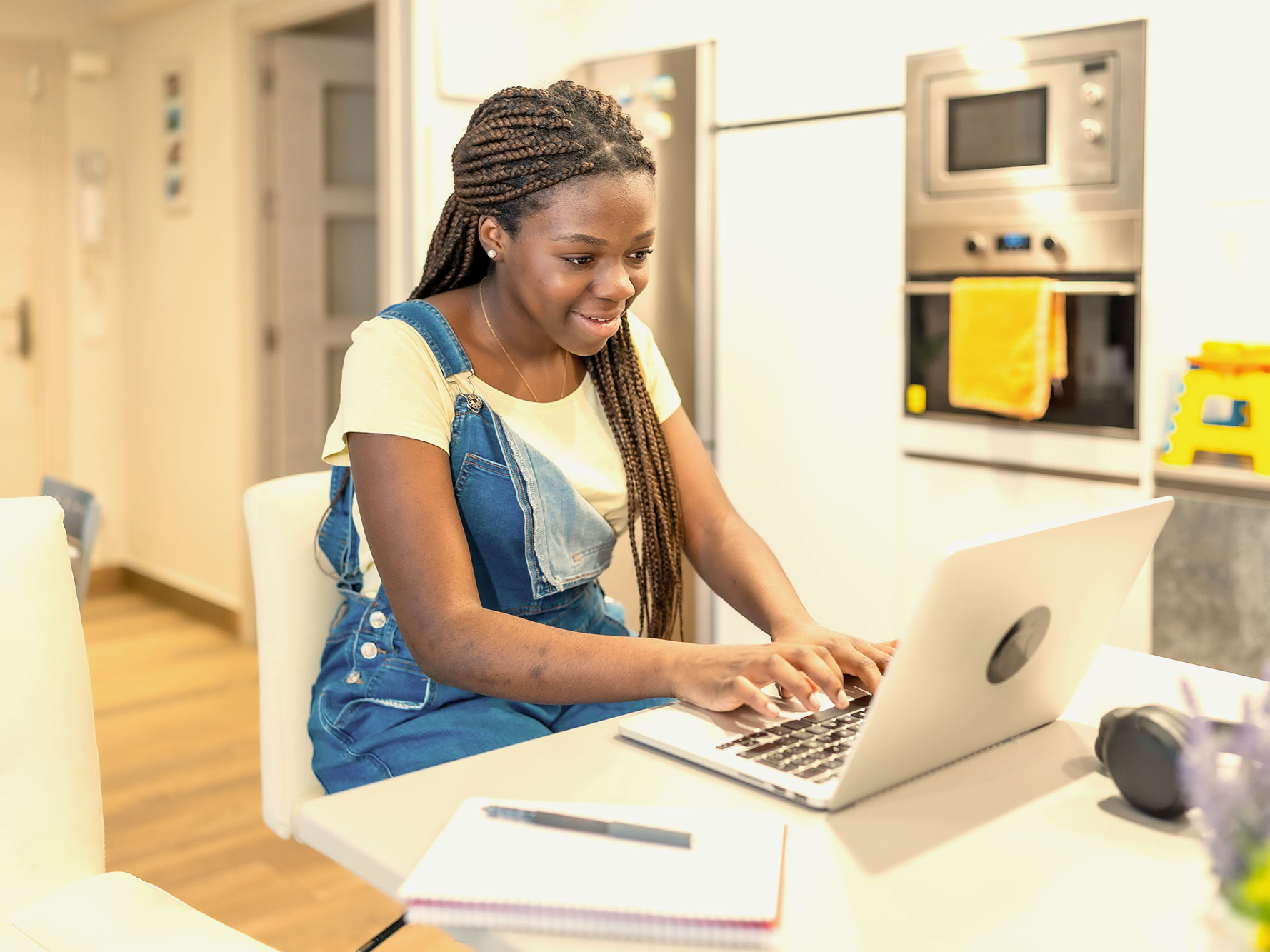 A smiling woman types on a laptop at a kitchen island.