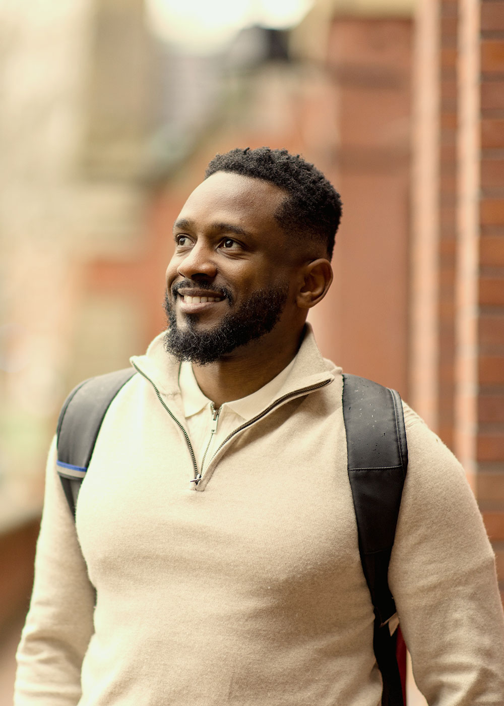 A Harvard Extension School student smiles as he stands outside a building on Harvard's campus.