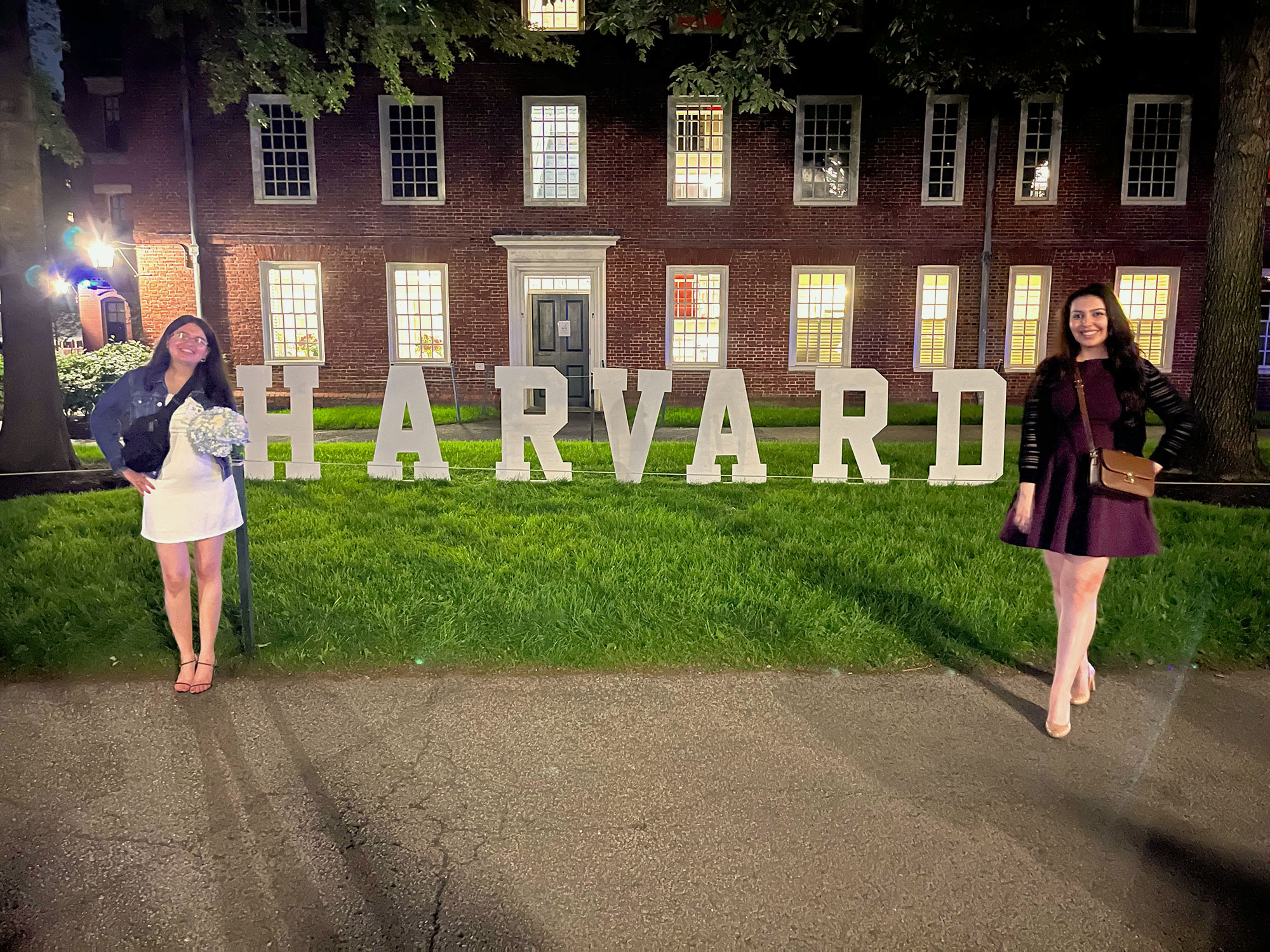 Basant and a friend pose for a photo next to a Harvard sign.