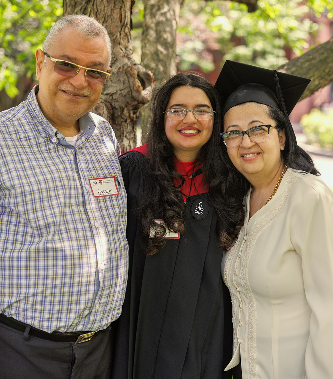 Basant poses for a photo at Commencement with her parents.