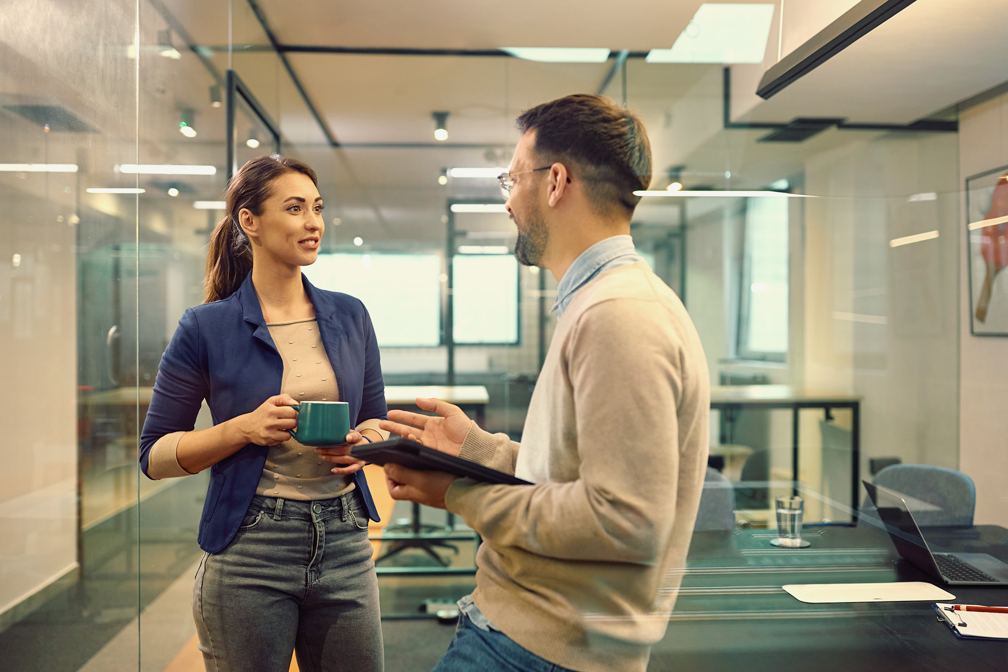 Two coworkers speaking in an office.