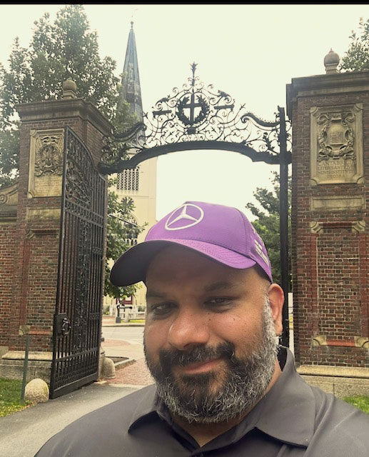 Harvard Extension School student Joslin Joseph in front of the Harvard gates.