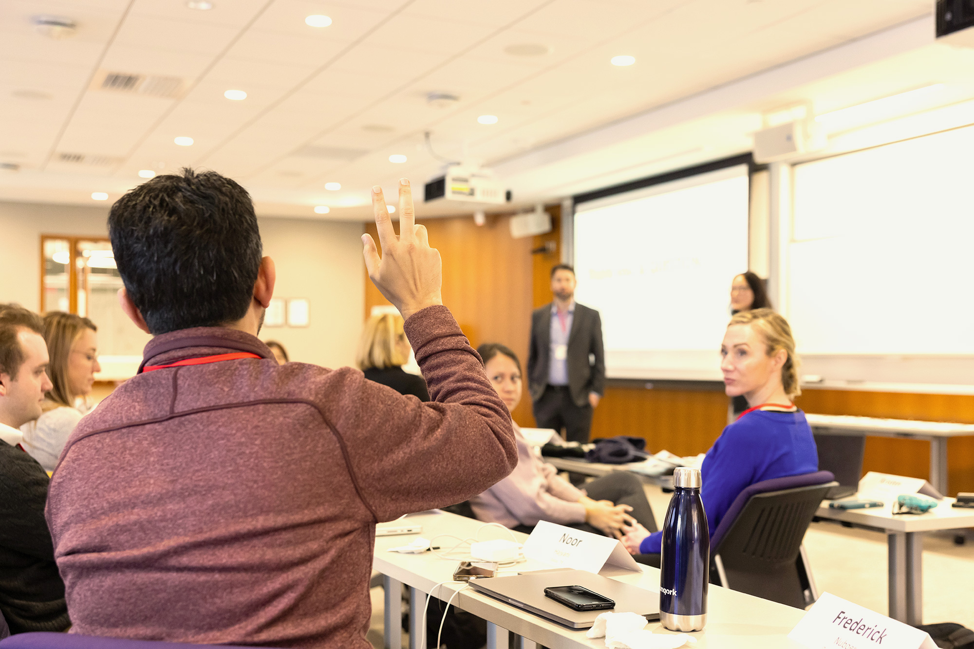 Student raising a hand in a classroom.