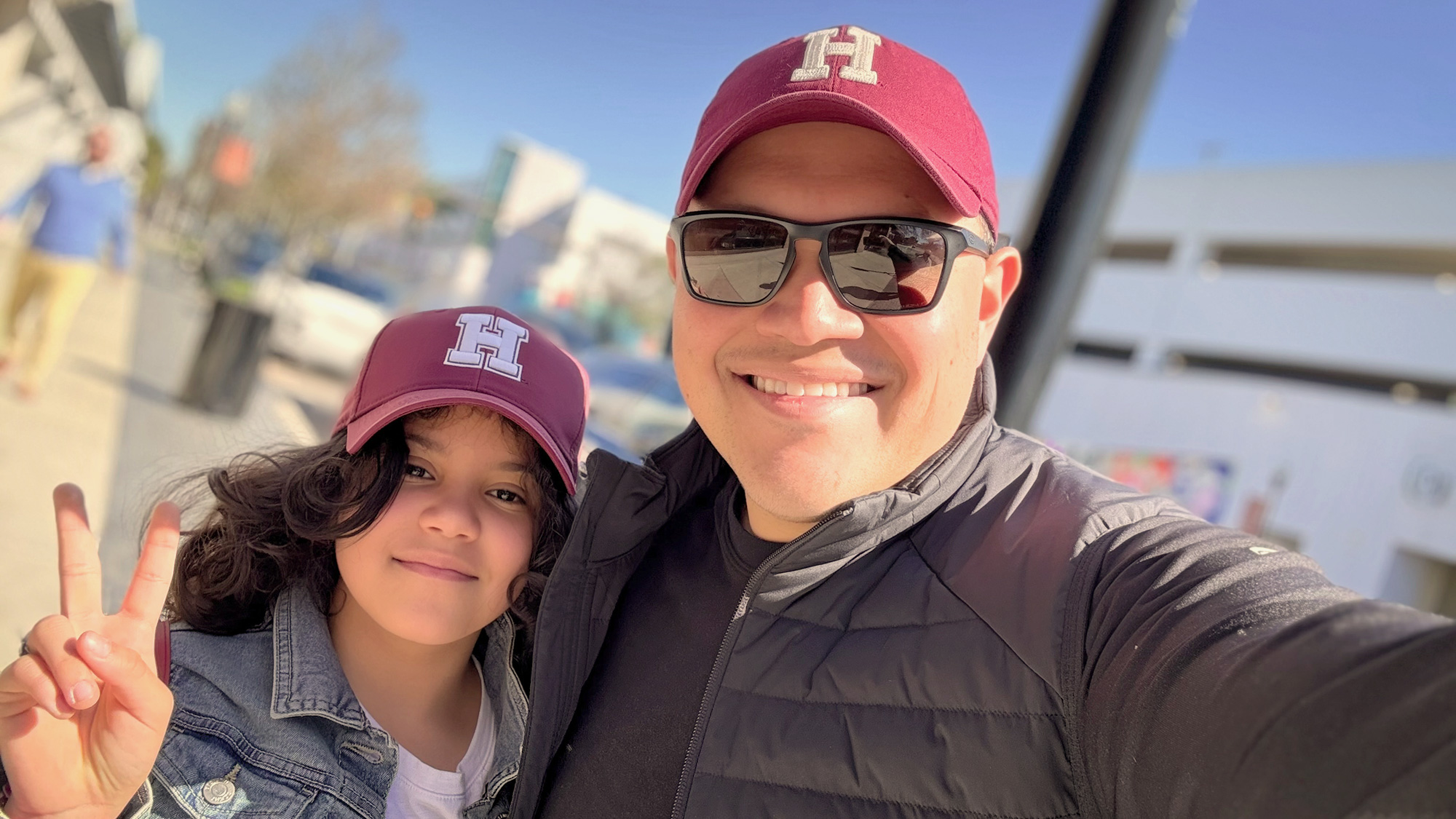 Jose with one of his daughters, wearing matching Harvard baseball caps.